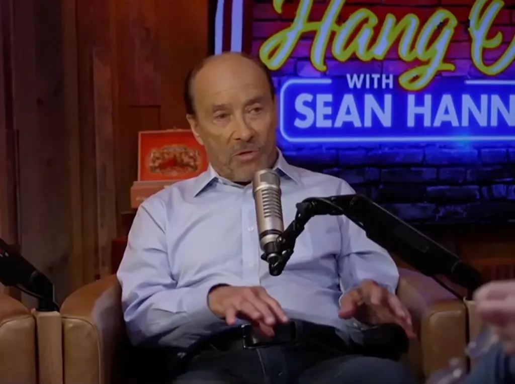 Lee Greenwood speaking into a microphone on Sean Hannity's podcast.