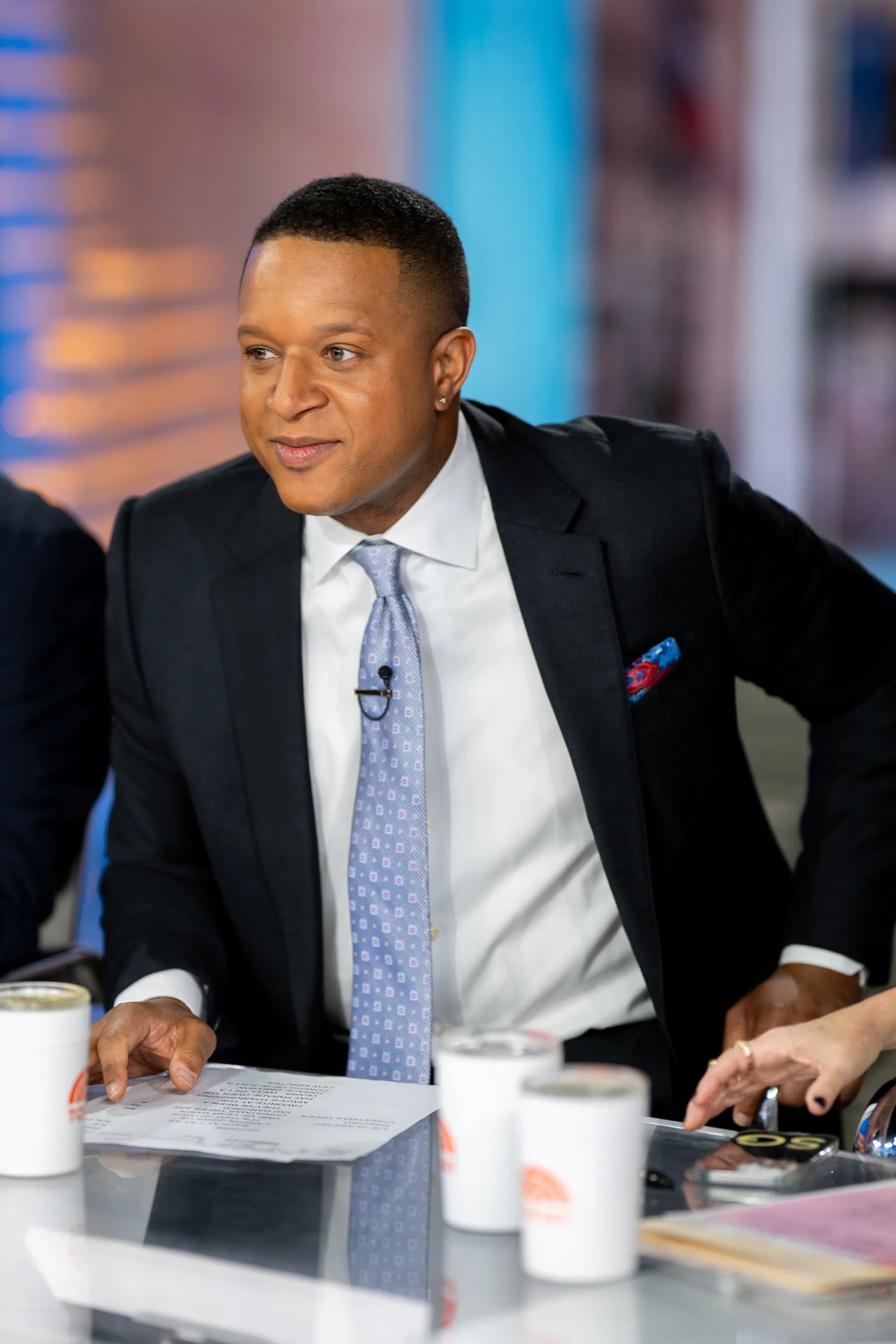 Craig Melvin, a Black man in a suit and tie, looking off to the side at the TODAY talk show set.