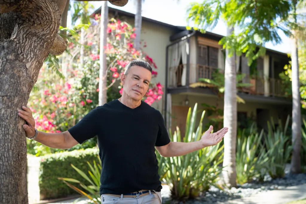Craig Ribeiro, owner of a four-unit apartment building, stands with his hands on a tree and gesturing.