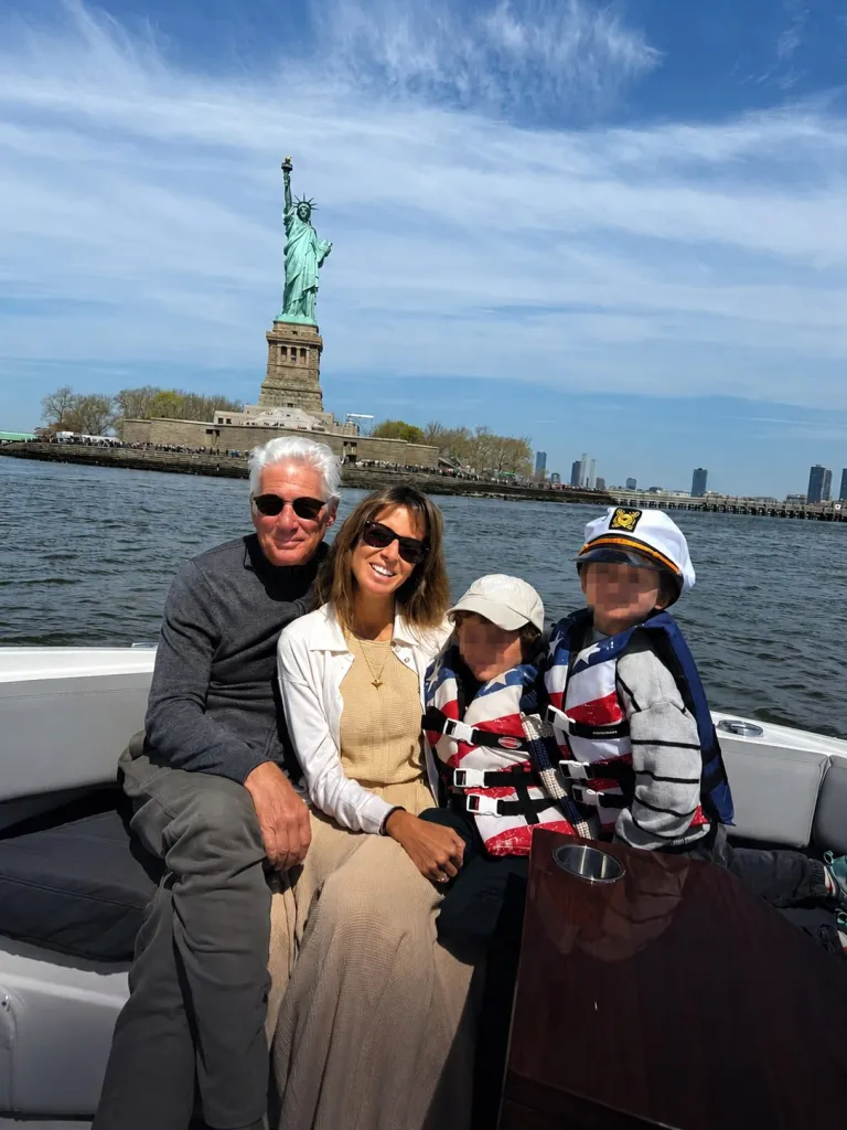 Richard Gere and his family on a boat with the Statue of Liberty in the background.