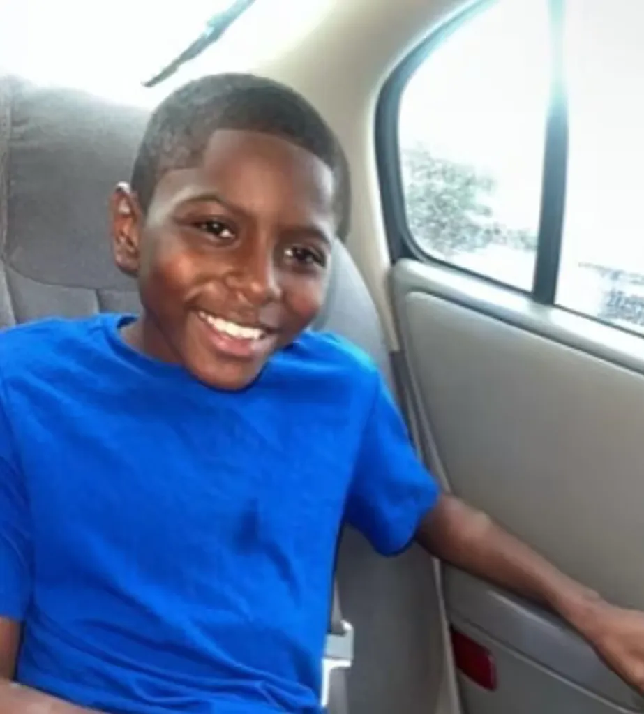Demarcus Shirley, a young boy with a bright smile, wearing a blue t-shirt, sitting in the back seat of a car.