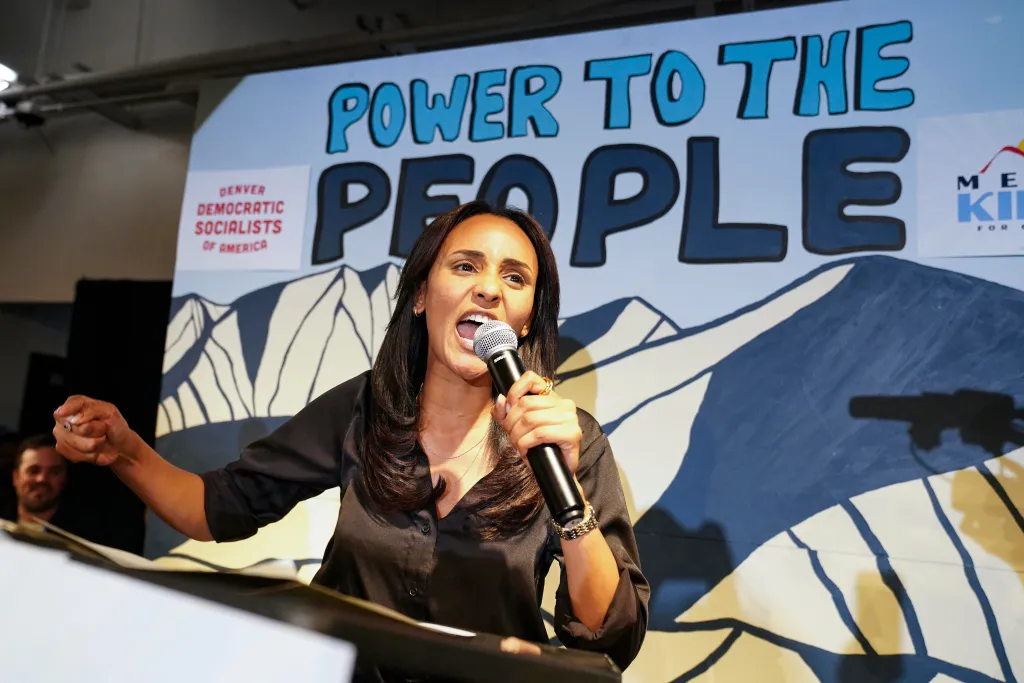 Melat Kiros speaking into a microphone with a backdrop that reads 