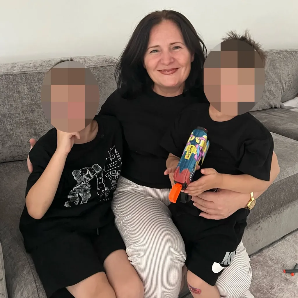 Donike Gocaj, the grandmother who died after falling into a Manhattan manhole, sitting on a couch with two young children.
