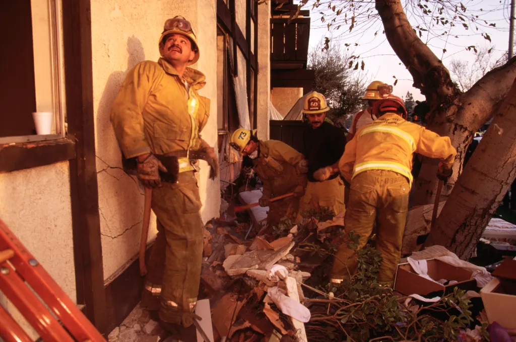 Four rescue workers sift through debris from an earthquake-damaged building.