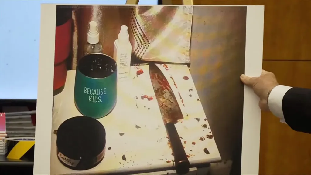Crime scene photo showing a bloodied kitchen knife next to a cup emblazoned with the message, 