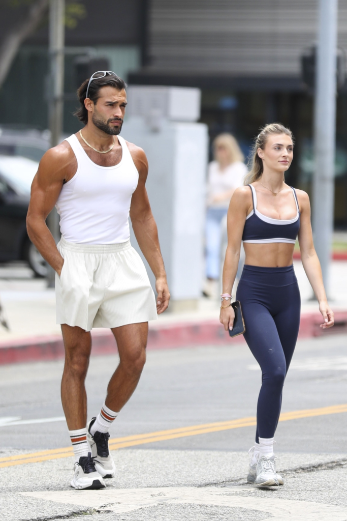Sam Asghari, in a white tank top and cream shorts and white sneakers, and Brooke Irvine, in a navy blue and white sports bra and blue leggings and whtie sneakers, shopping for home decor in Beverly Hills.
