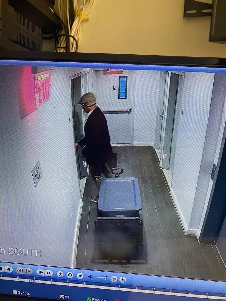 CCTV footage showing Sheldon Johnson in a hallway with a large cooler on a dolly.