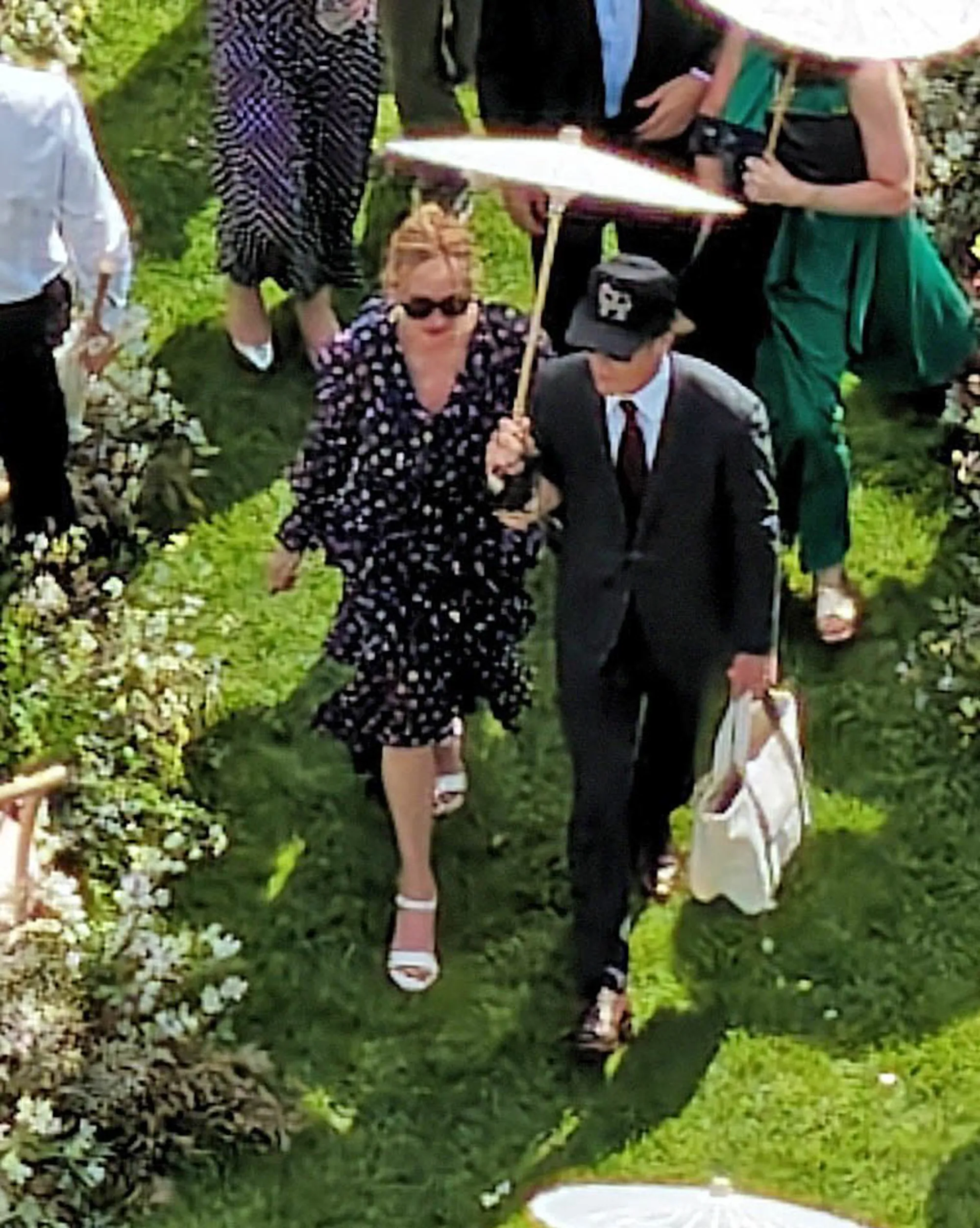 Julia Roberts and Daniel Moder walk together, shielding themselves from the sun with a white parasol.