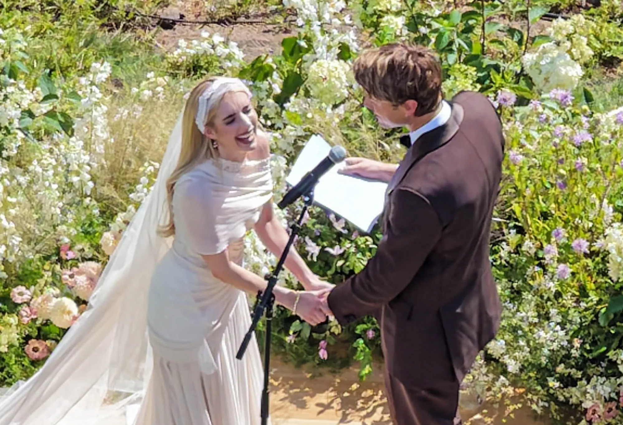 Emma Roberts and Cody John holding hands and smiling during their wedding ceremony.