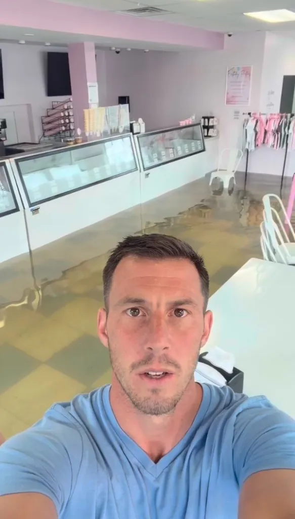 A man in an ice cream shop with floodwaters covering the floor.