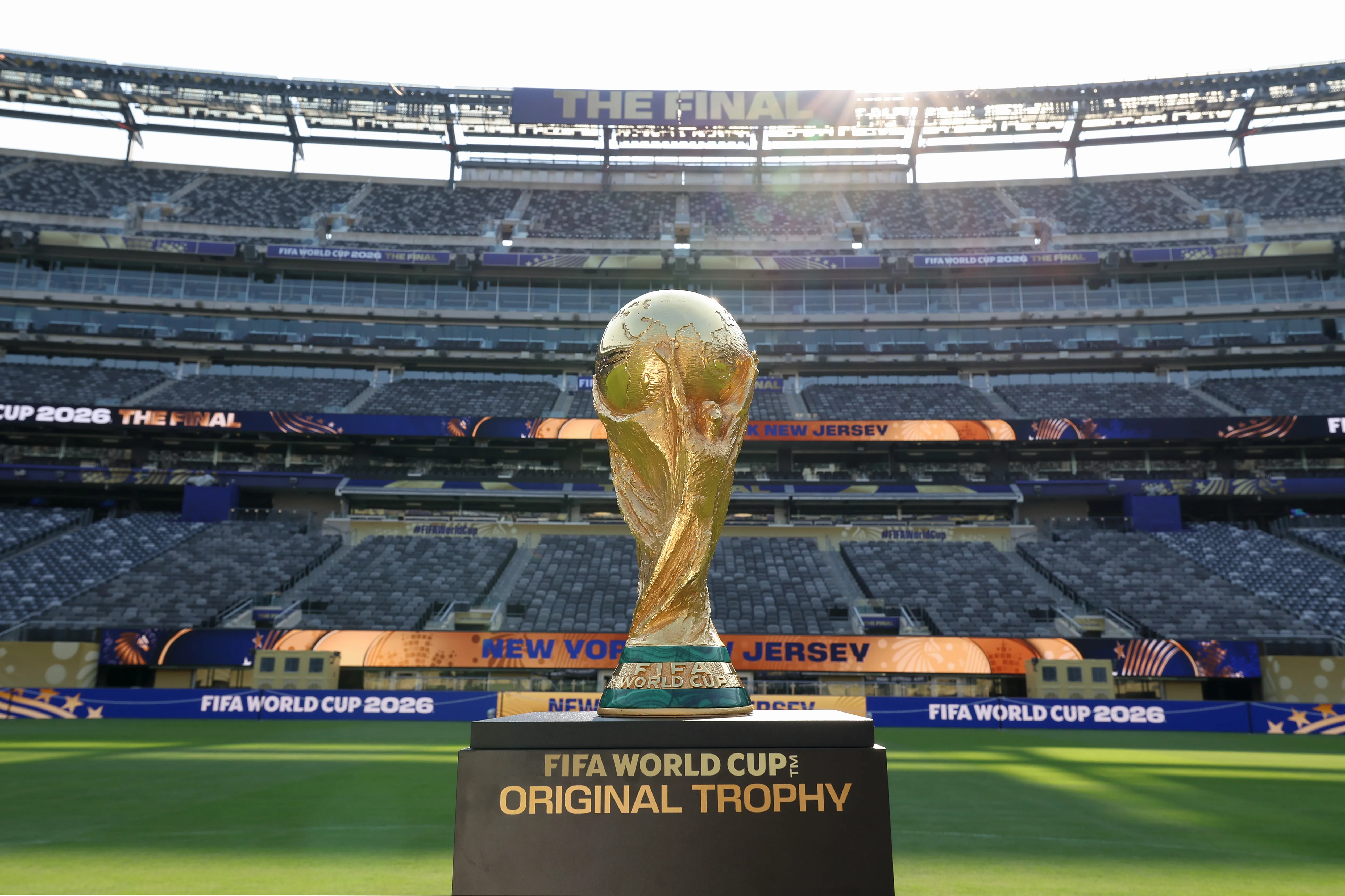 The FIFA World Cup Trophy displayed in an empty stadium, with the text