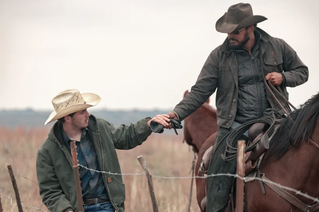 Rip Wheeler on horseback handing gloves to Carter.