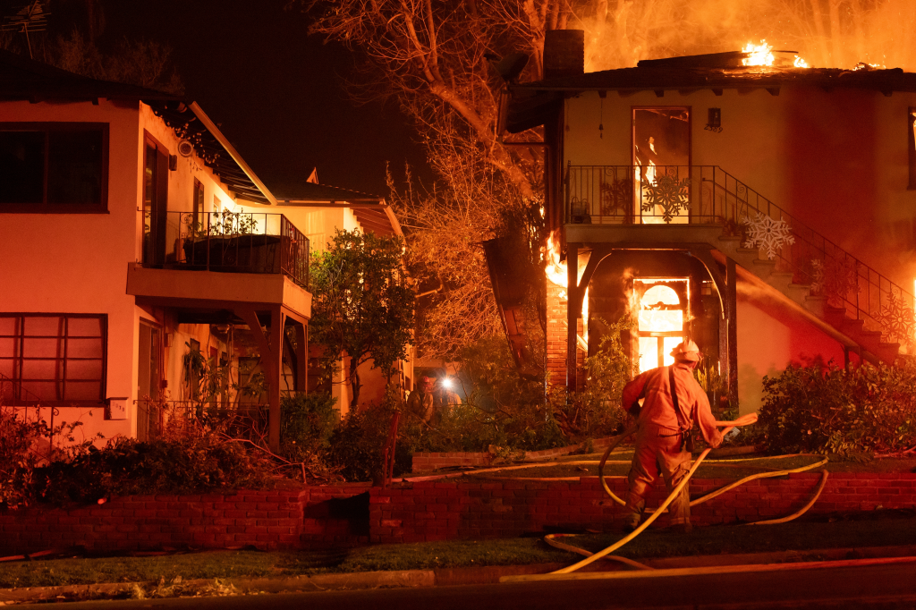 Firefighters extinguishing a blaze at an apartment complex at night.