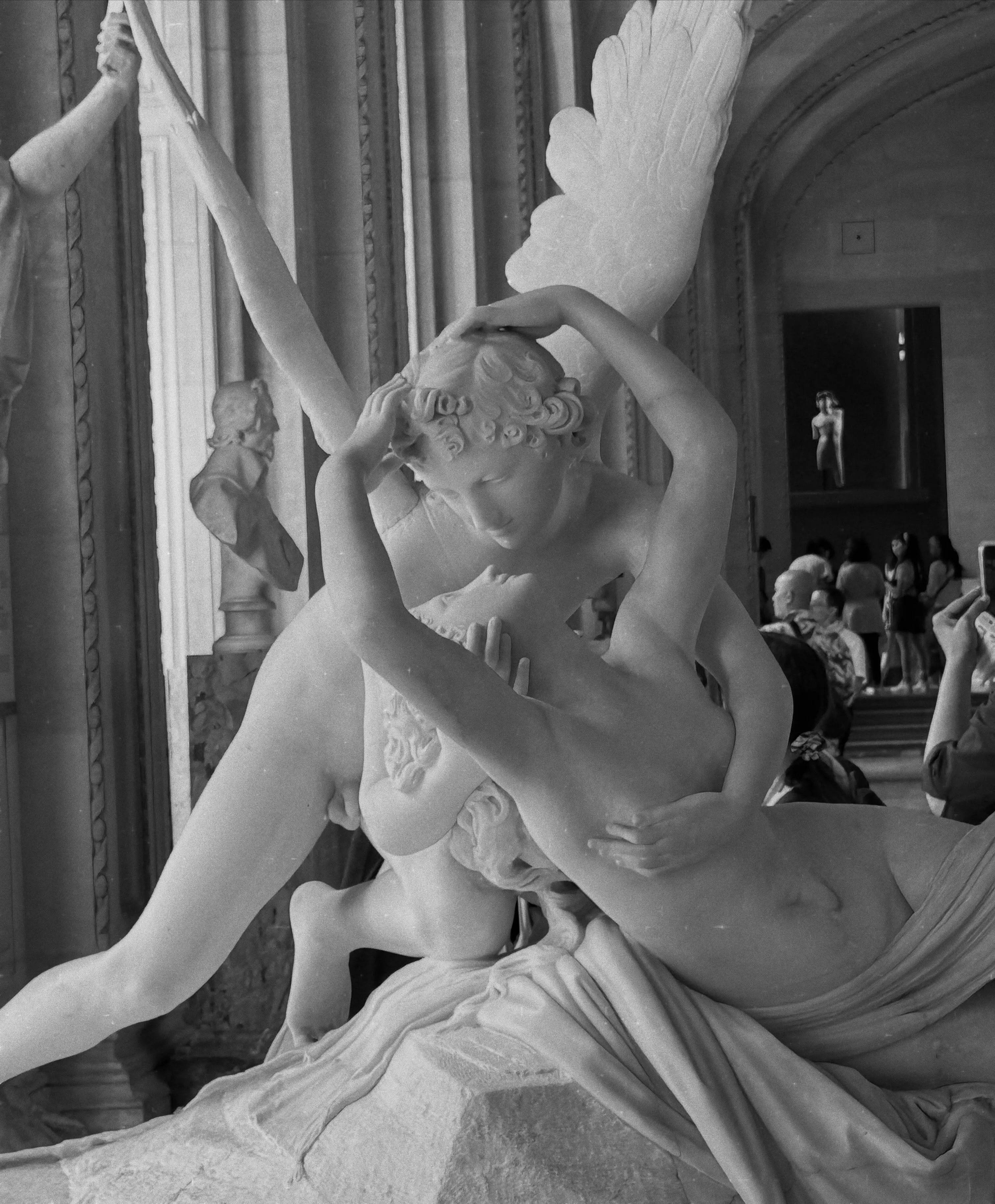 A black and white photo of a romantic marble sculpture from the Louvre Museum in Paris, depicting Cupid kissing Psyche.