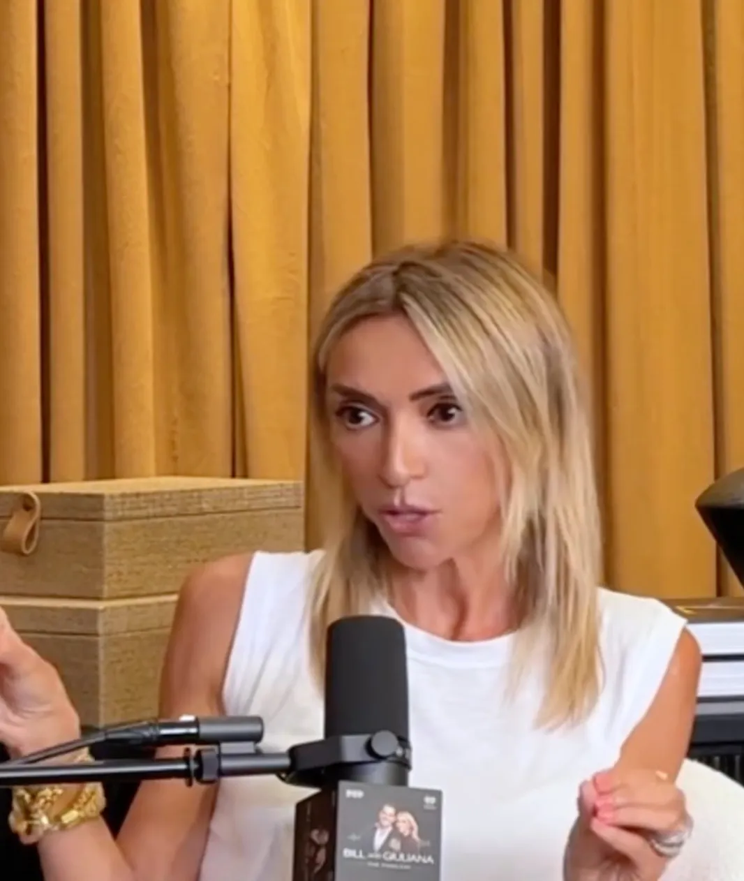 Giuliana Rancic speaking into a microphone with her podcast logo visible.