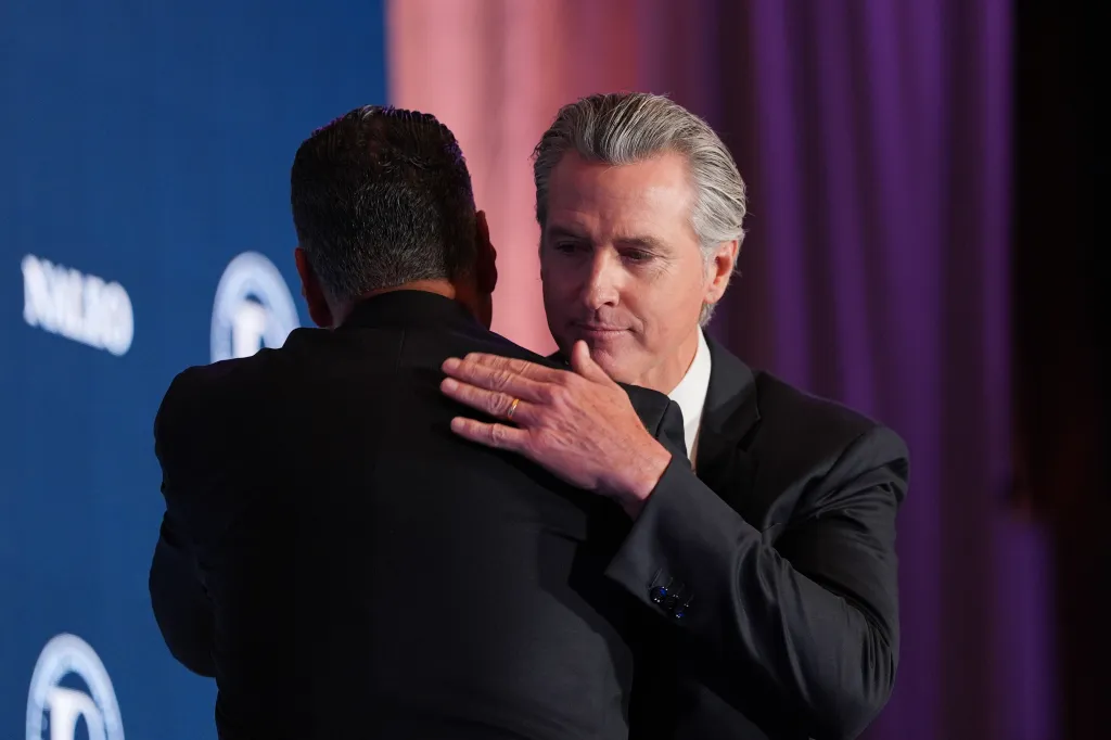 Gavin Newsom hugs Alex Padilla.