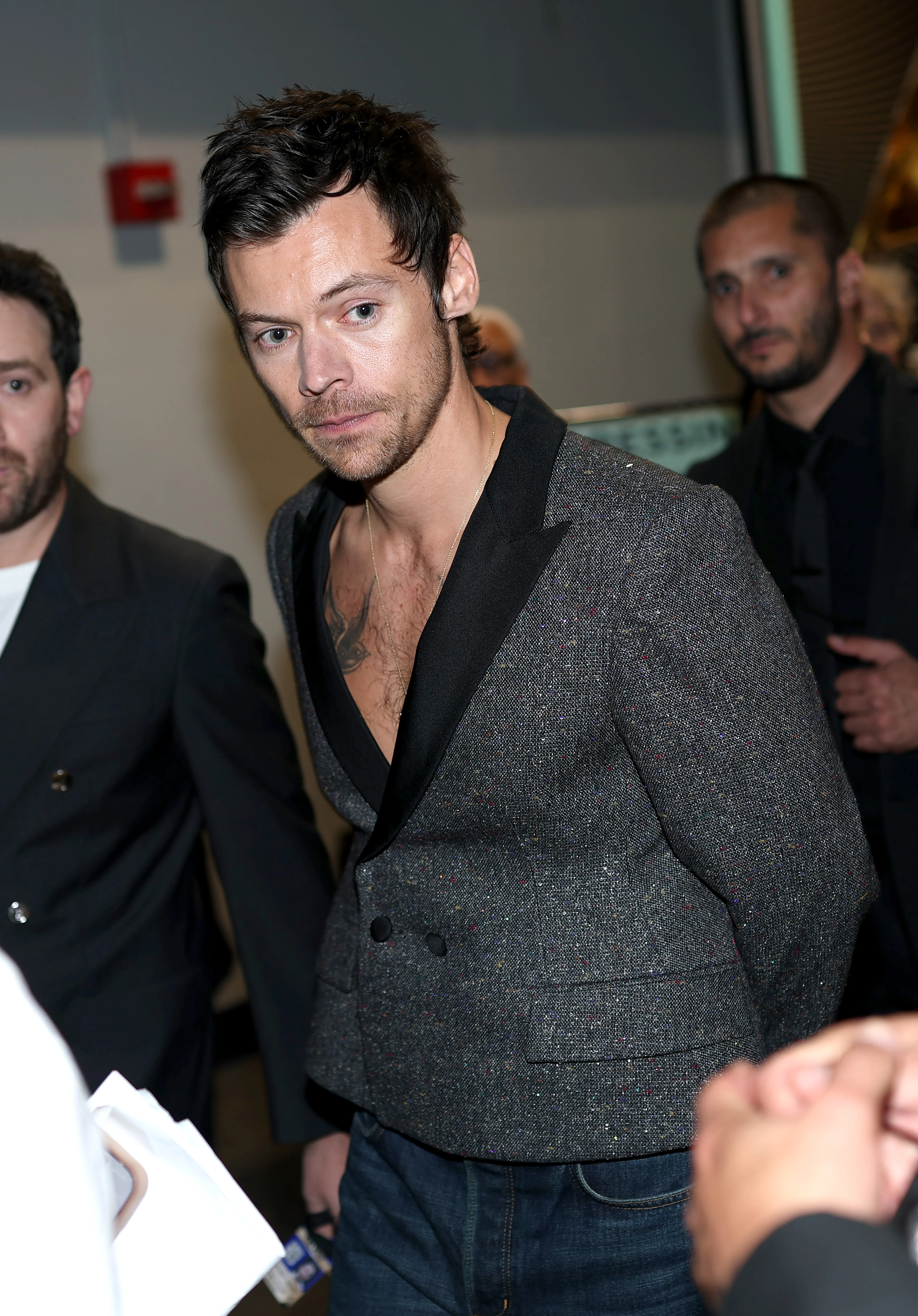 Harry Styles at the 68th GRAMMY Awards, wearing a tweed jacket over a bare chest.