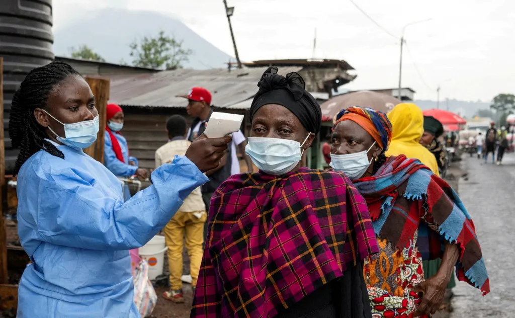 A health worker checks the temperature of a woman at a border checkpoint.