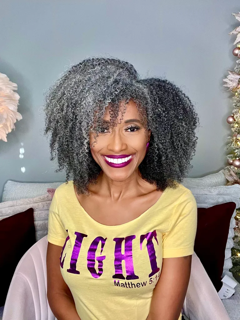 Karen Flowers smiling at the camera, wearing a yellow t-shirt with the word