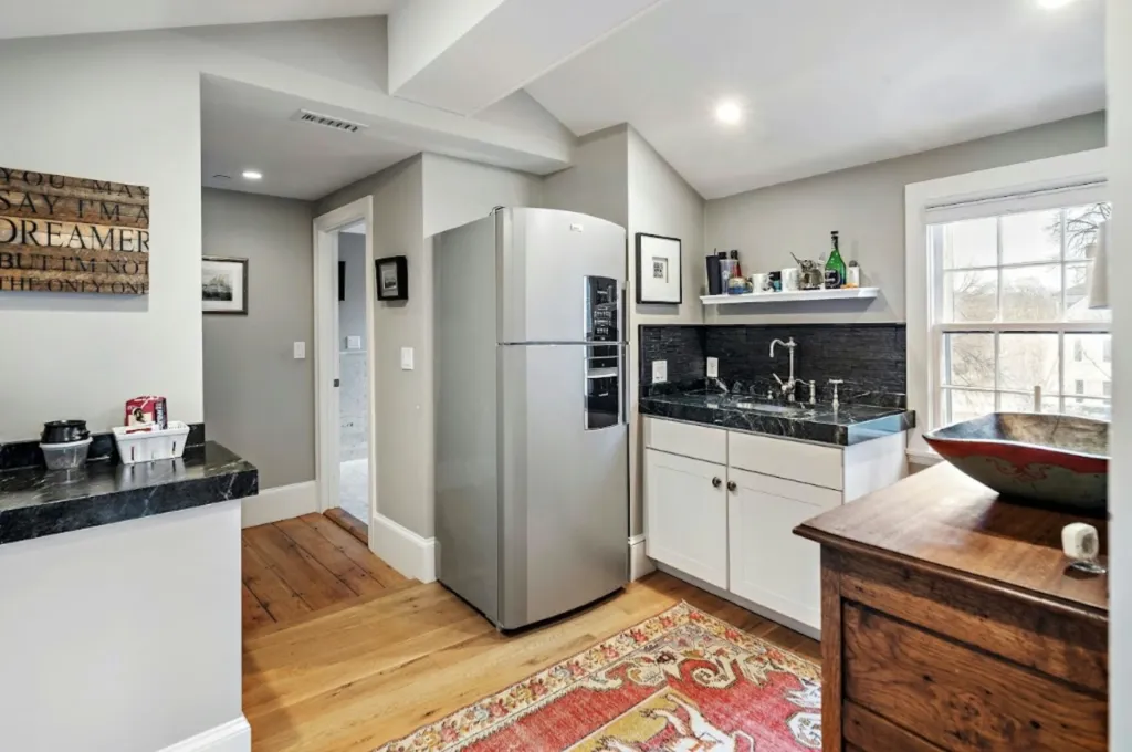 Kitchen in the Lindall-Gibbs-Osgood House with dark countertops, white cabinets, and a gray refrigerator.