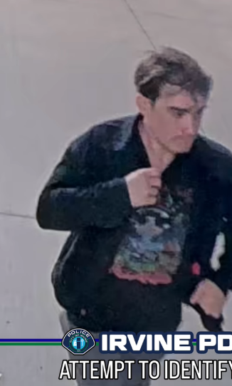 Mugshot of a man with light brown hair, wearing a black jacket and a dark graphic t-shirt.