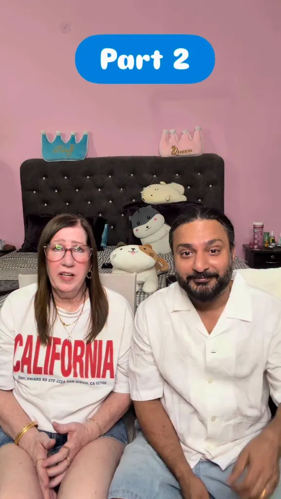 Jenny Slatten and Sumit Singh sitting together in a bedroom setting, with a bed behind them decorated with stuffed animals and crown-shaped pillows.