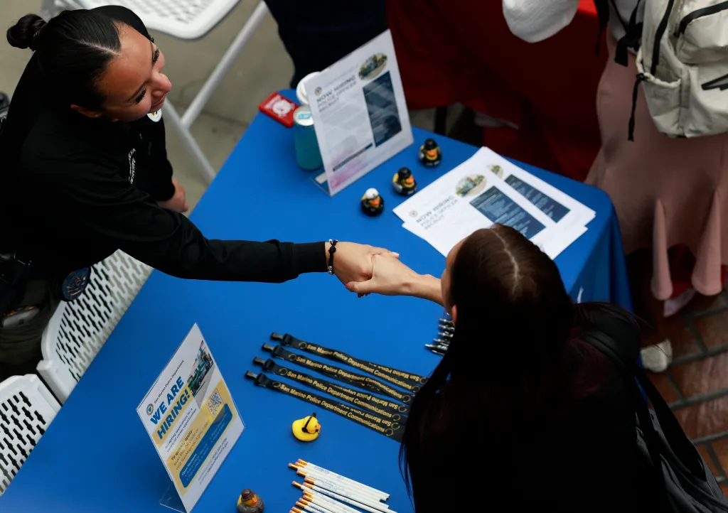A recruiter and a job seeker shaking hands at a job fair in Los Angeles.