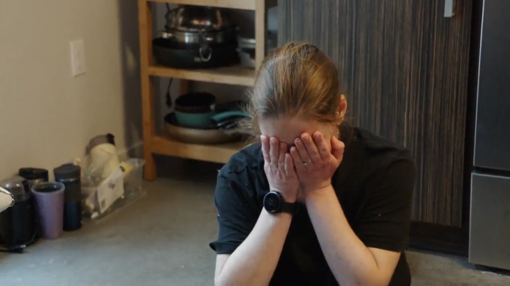 Catie covers her face with her hands.