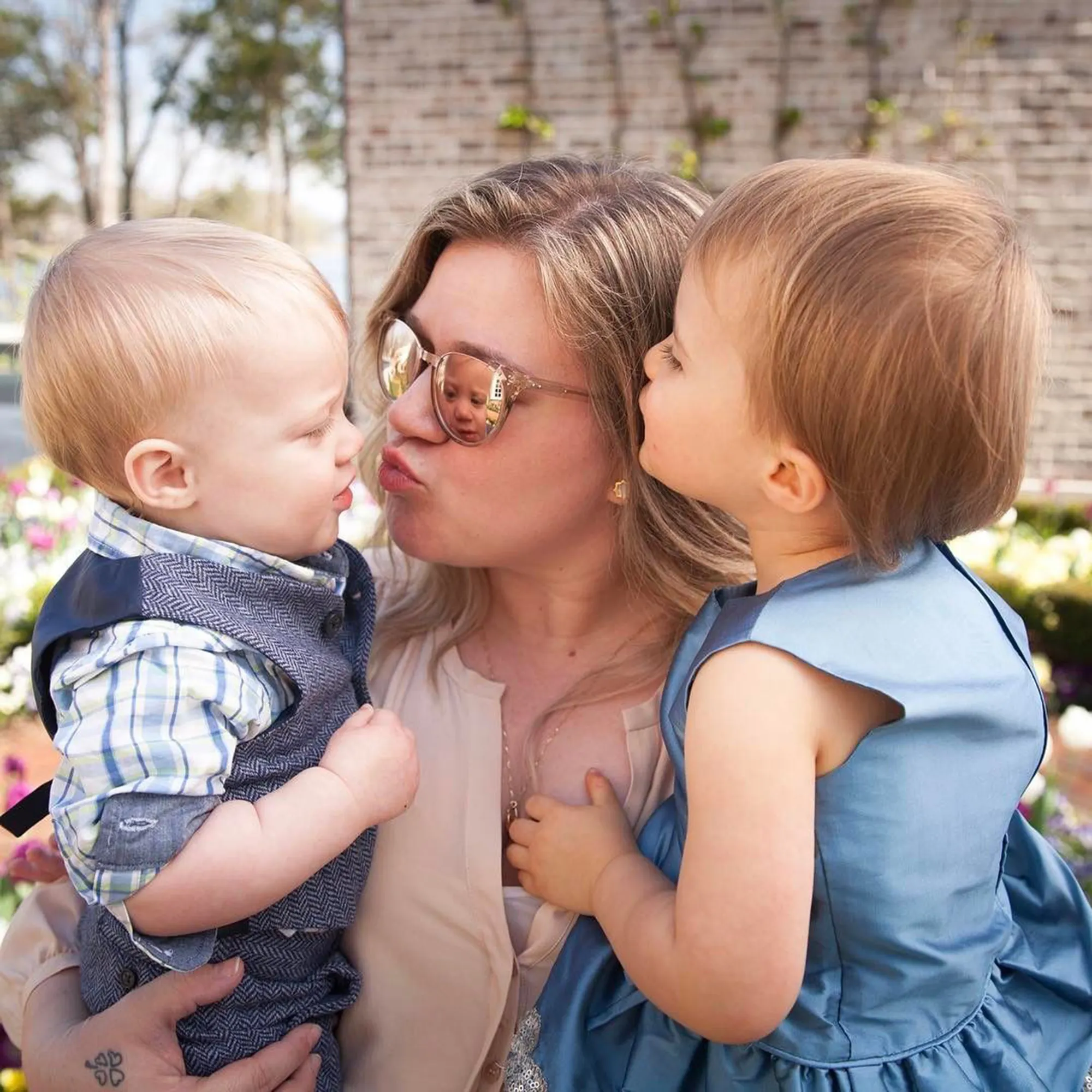 Kelly Clarkson making a kissy face with her two children, River and Remy.