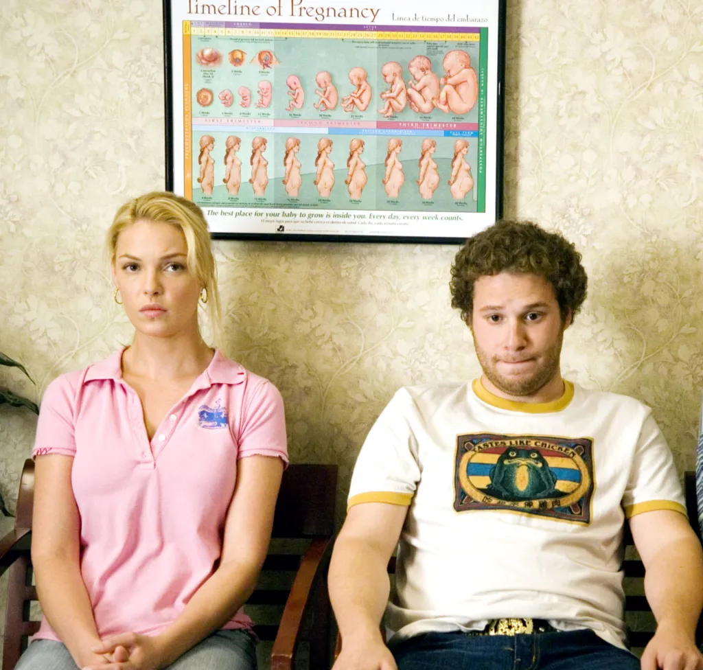 Katherine Heigl and Seth Rogen as a nervous couple sitting in a waiting room with a 
