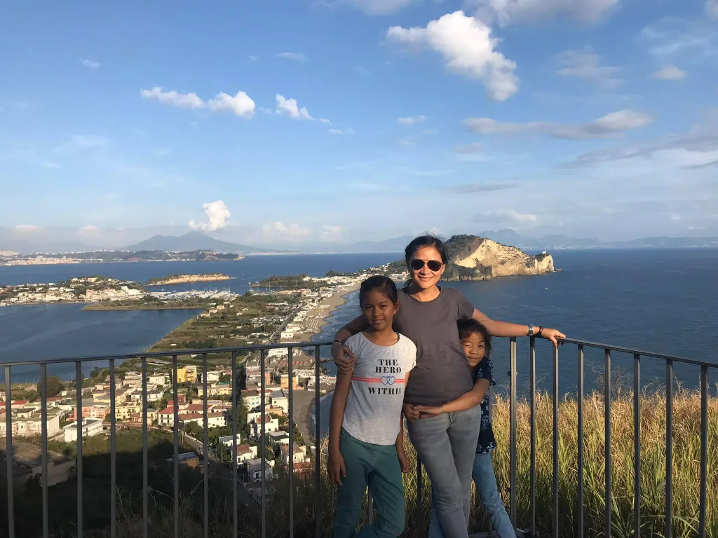 Maya Millete with her two daughters overlooking a coastline town.