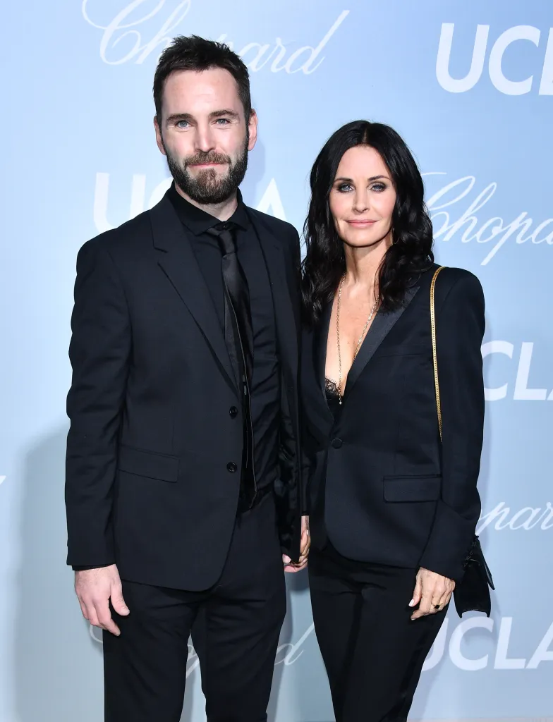 Johnny McDaid and Courteney Cox posing on a red carpet.