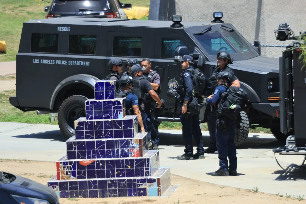 Members of the Los Angeles Police Department stand around a large black armored truck.