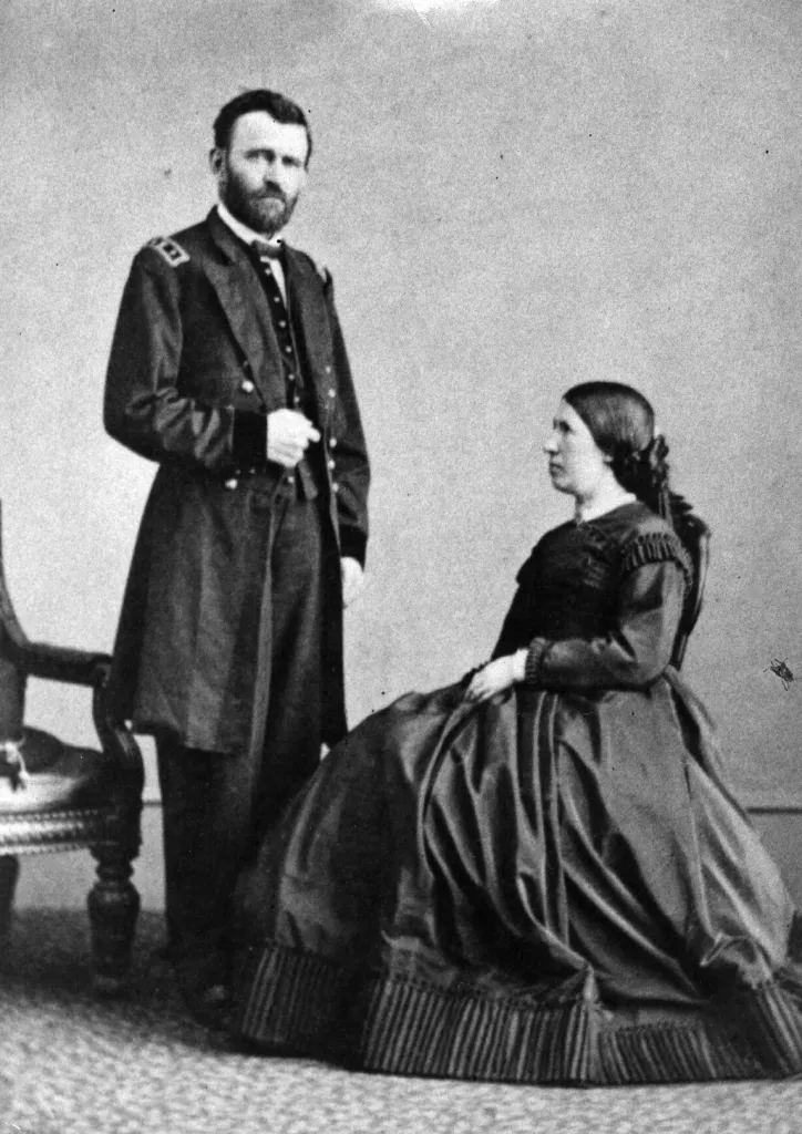 Ulysses S. Grant, in military uniform, standing beside his wife Julia Grant, seated in a long dark dress.