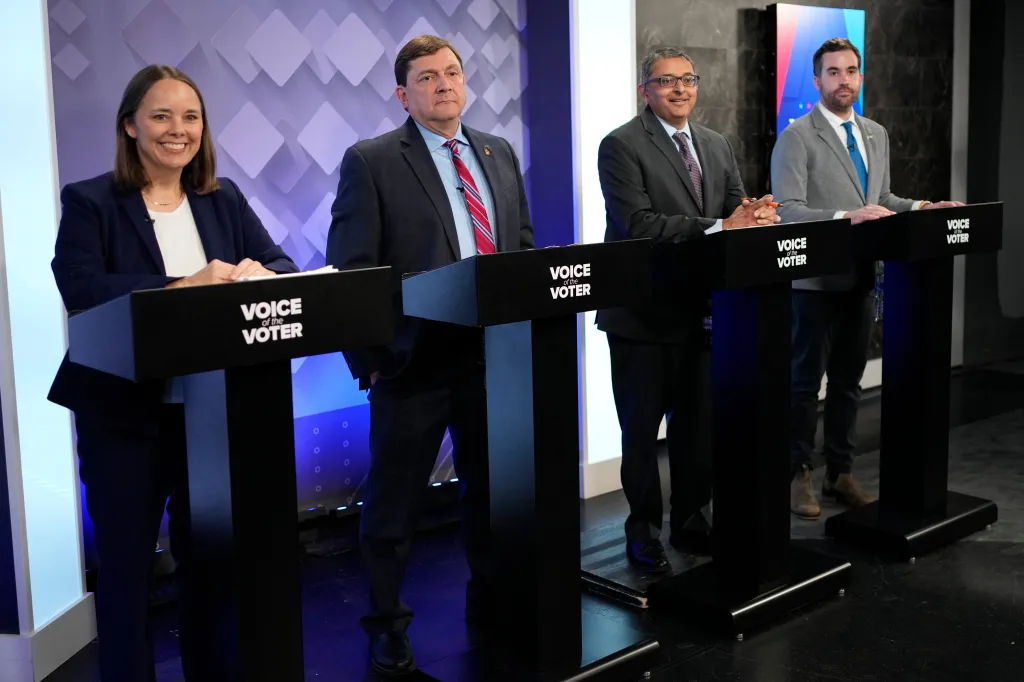 Four U.S. Senate hopefuls for Maine, Shenna Bellows, Troy Jackson, Dr. Nirav Shah, and Jordan Wood, stand behind podiums during a televised debate.