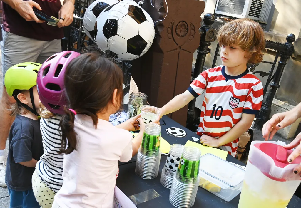 Mason Whittaker sells lemonade to kids at a soccer-themed lemonade stand.