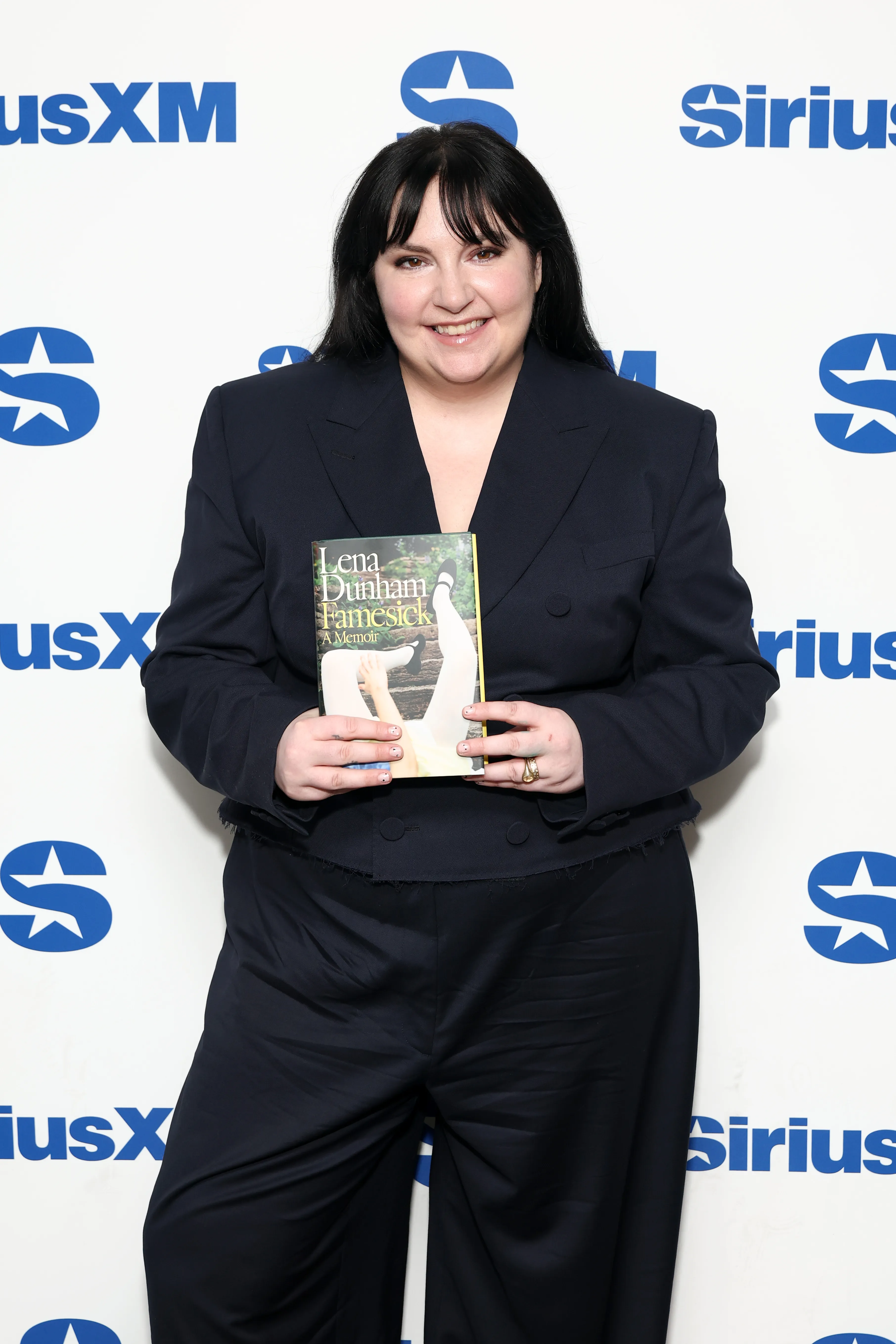 Lena Dunham holds her book 