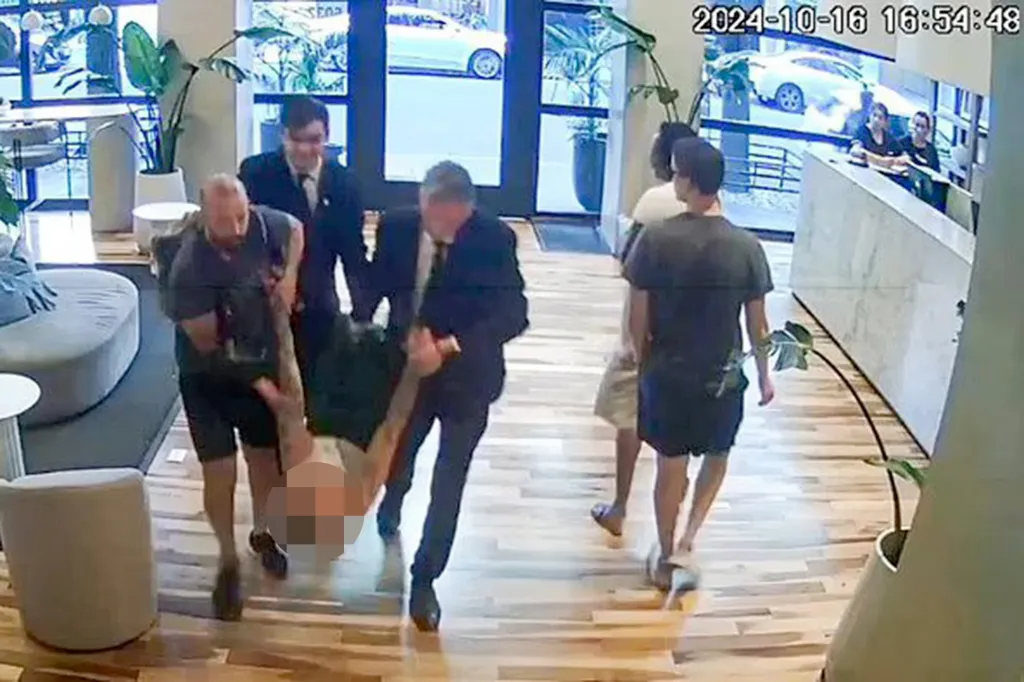 Three men carrying Liam Payne through a hotel lobby.