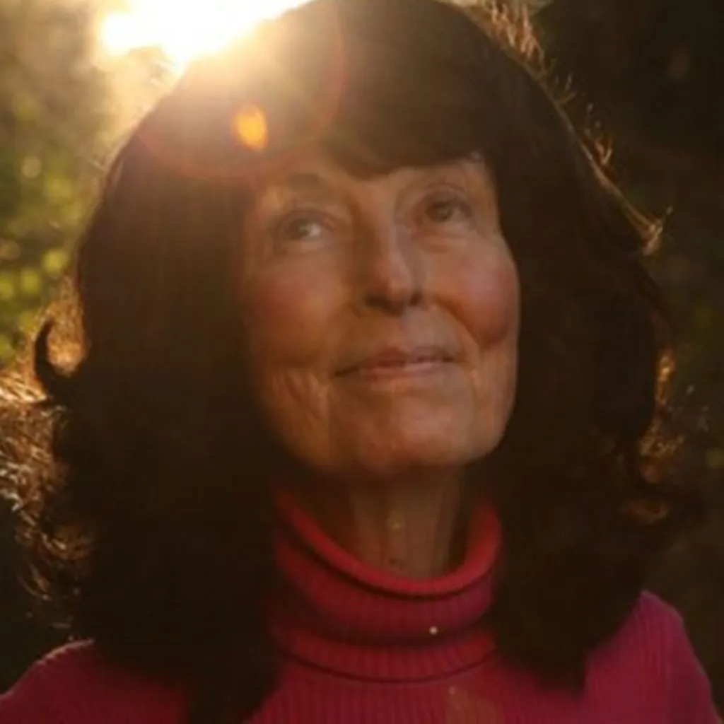 Linda Perhacs, a woman with dark hair and a red turtleneck, smiling softly.