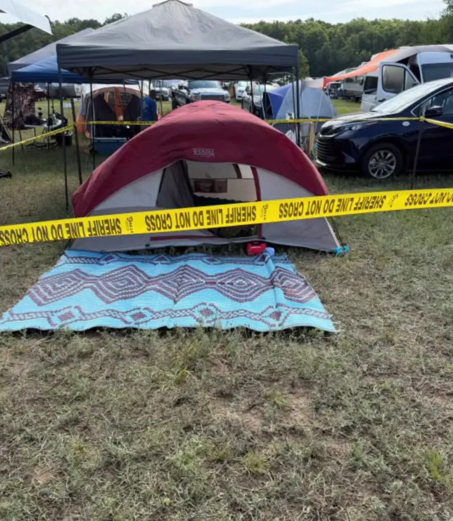 A red and gray tent with a blue mat in front, cordoned off by yellow 