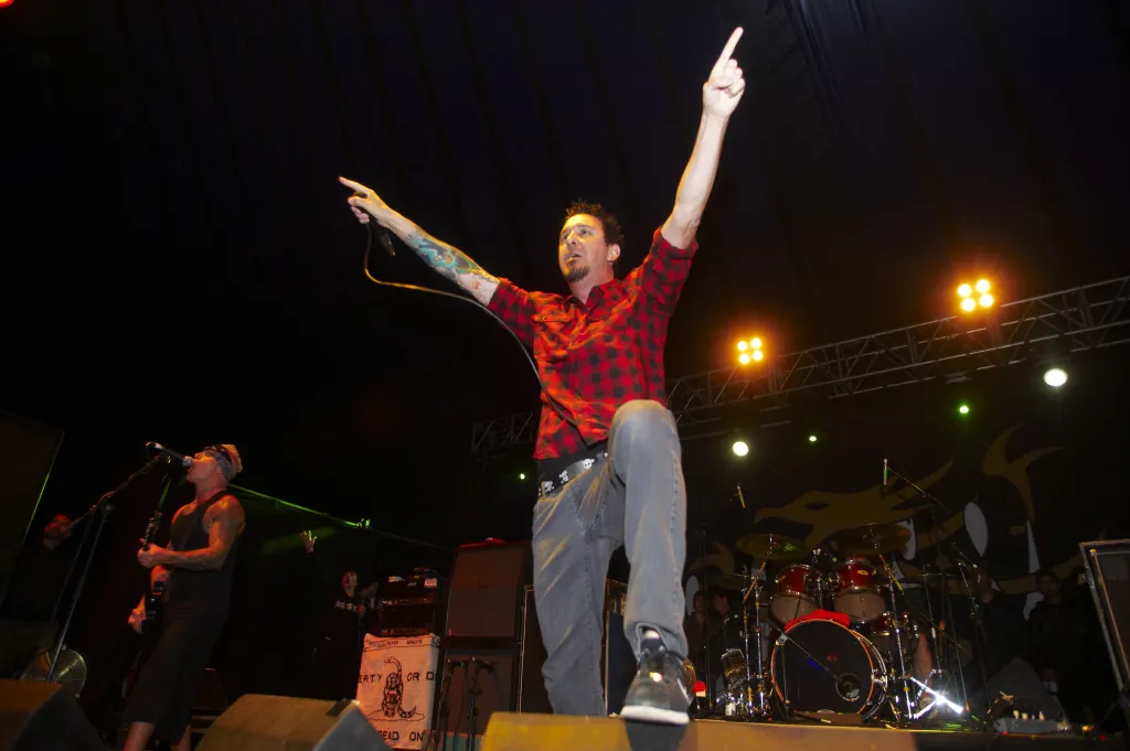 Lou Koller of Sick Of It All performs on stage with arms raised.