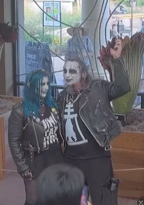 Gothic couple engaged in front of a corpse flower.