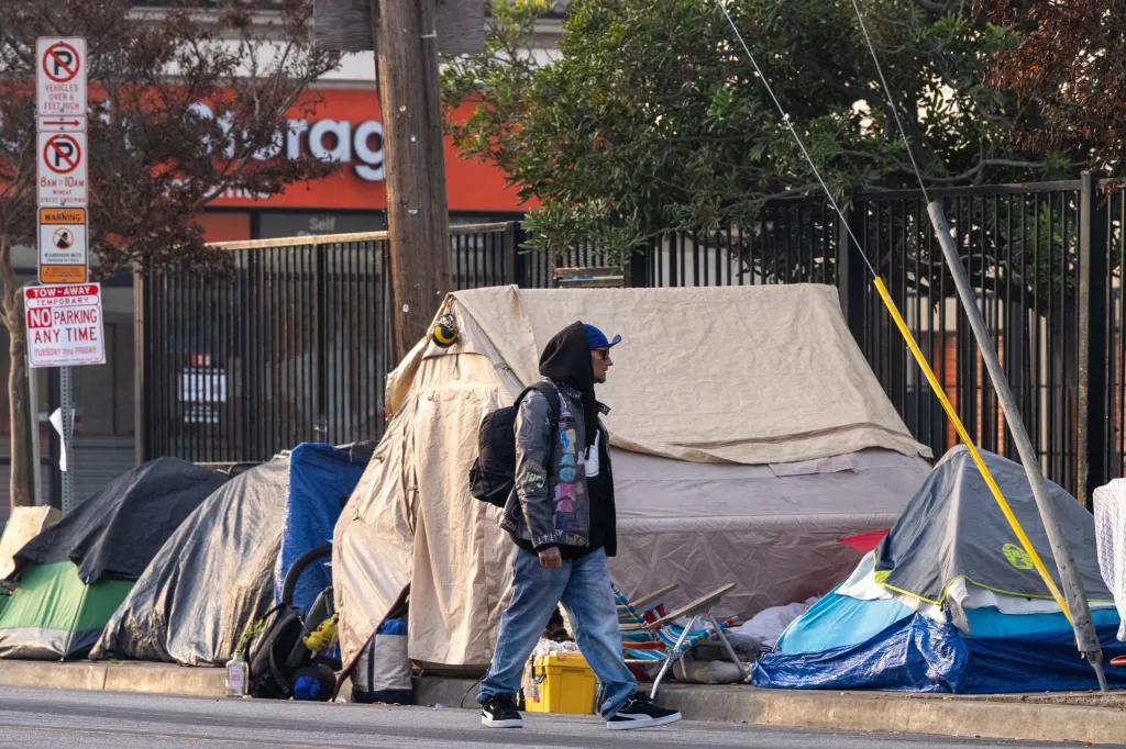 A man walks past tents at a homeless encampment on 3rd Street in Venice, California.