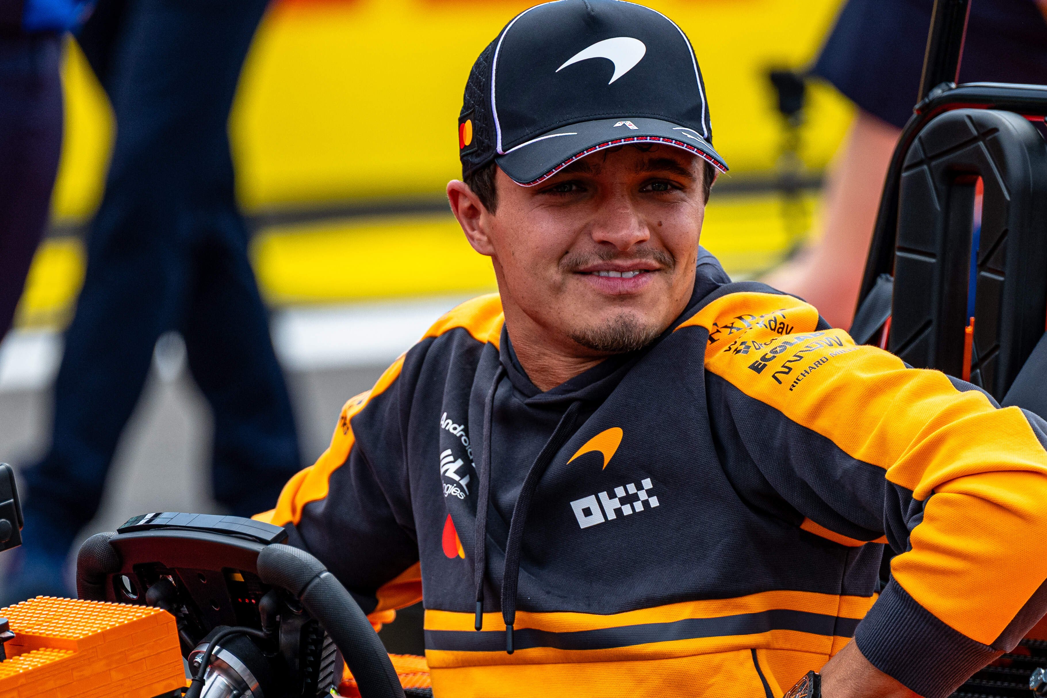 Lando Norris wearing a black and orange McLaren F1 Team hoodie and cap.