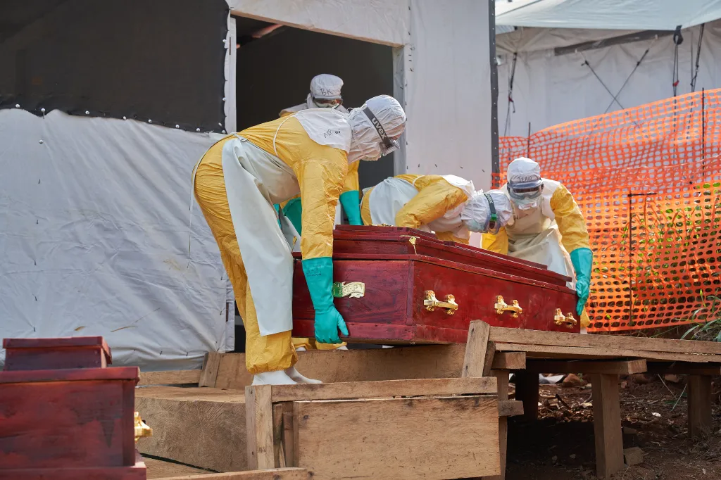 Staff in full protective gear carry a coffin for an Ebola victim in Mongbwalu, Democratic Republic of Congo.
