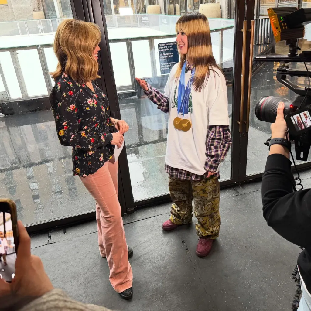 Sara Gore interviewing a young woman with Olympic medals.