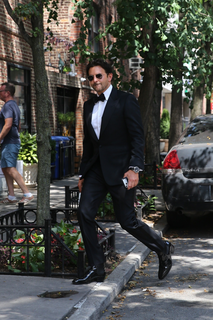 Bradley Cooper in a tuxedo, walking on a city street.