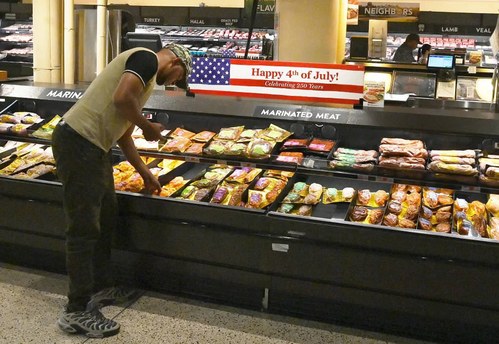 A shopper at Wegmans .looks at packaged marinated meats in a grocery store with a 