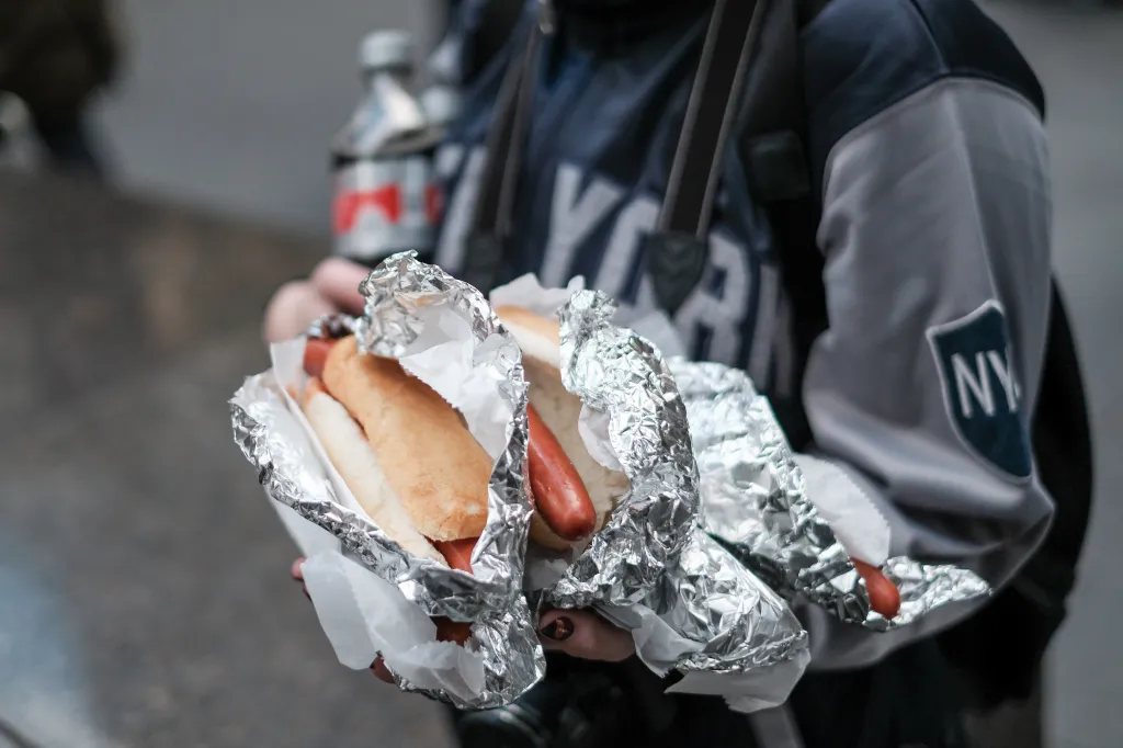 Five hot dogs wrapped in foil and paper.