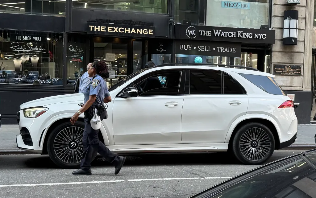 Traffic agent walking past a white SUV parked in front of jewelry stores on West 47th St.